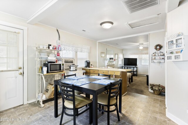 dining space featuring carpet, ceiling fan, and crown molding