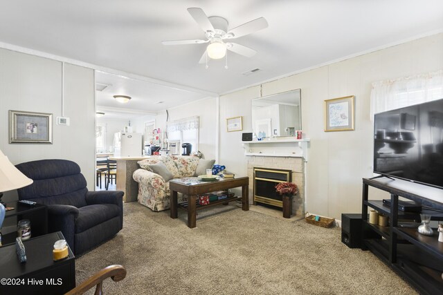 living room featuring carpet flooring, ceiling fan, a fireplace, and ornamental molding