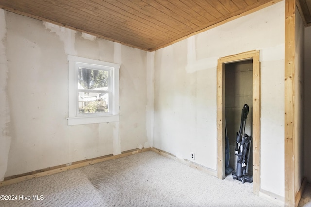 carpeted spare room featuring wooden ceiling