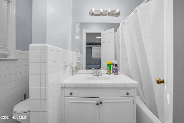 full bathroom featuring shower / bath combination with curtain, vanity, toilet, and tile walls