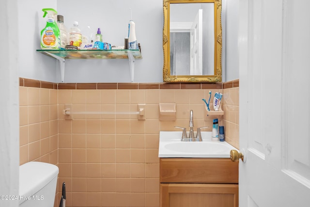 bathroom featuring vanity, toilet, and tile walls