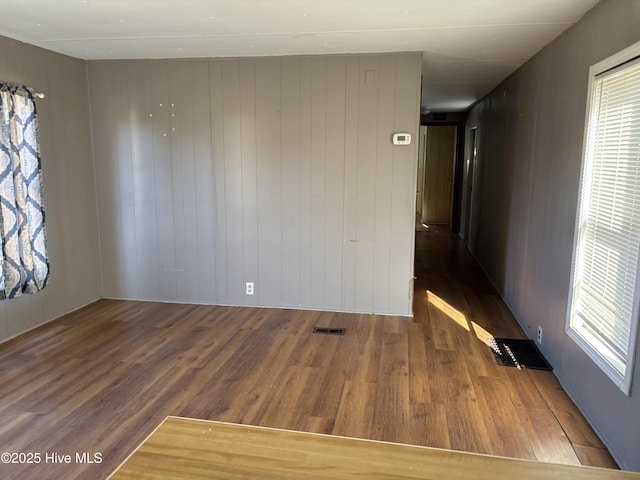 spare room with dark hardwood / wood-style flooring and wooden walls