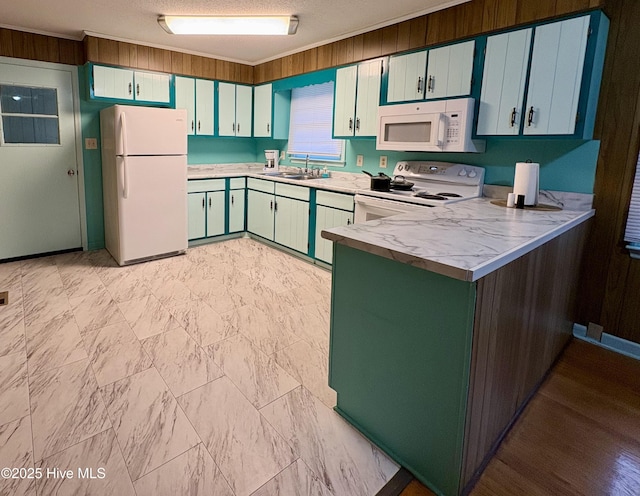 kitchen featuring wood walls, sink, kitchen peninsula, crown molding, and white appliances