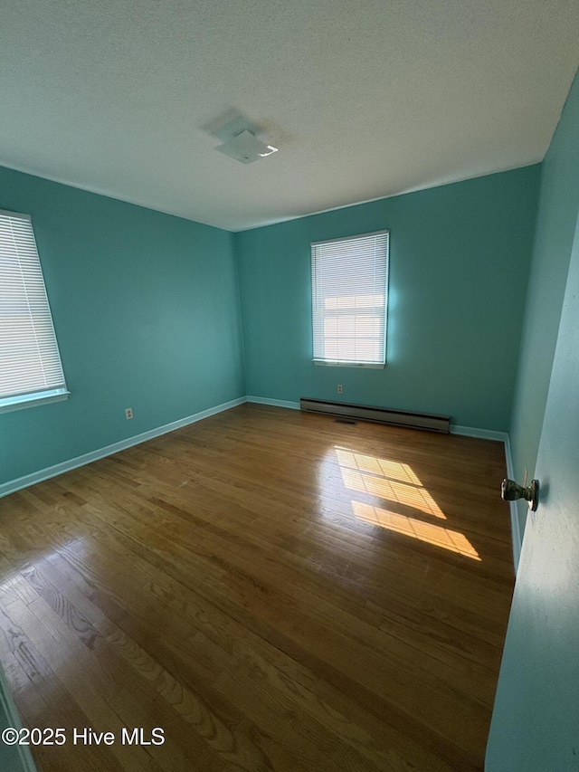 1394 Lake Cole Rd, Midway Park, NC 28544 - spare room with a baseboard heating unit, wood finished floors, baseboards, and a textured ceiling