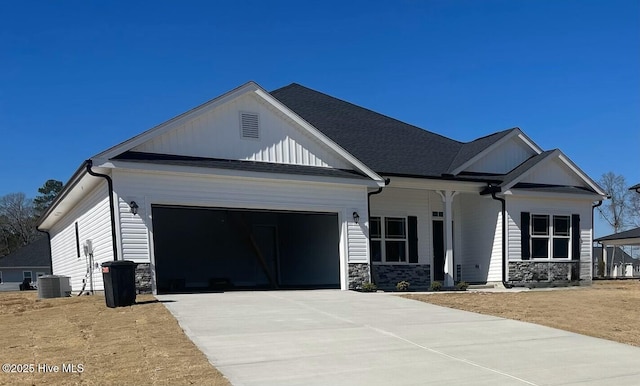 craftsman-style home featuring driveway, a garage, stone siding, cooling unit, and board and batten siding