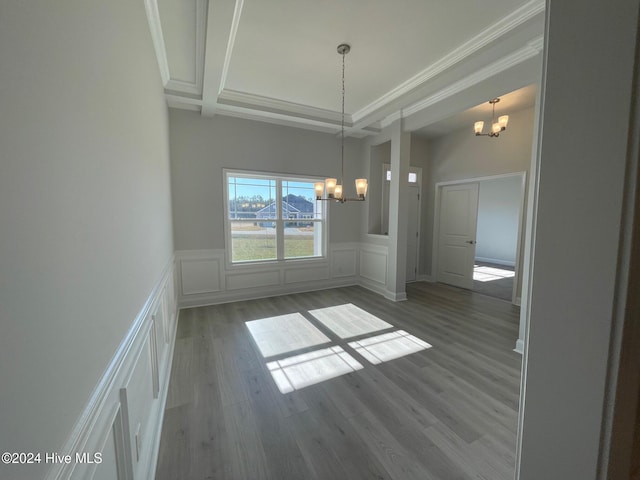 unfurnished dining area with an inviting chandelier, ornamental molding, and hardwood / wood-style floors