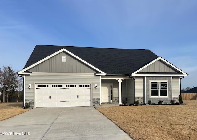 craftsman inspired home with a garage, concrete driveway, stone siding, a front lawn, and board and batten siding