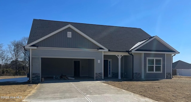 craftsman-style home featuring a garage, concrete driveway, stone siding, roof with shingles, and covered porch