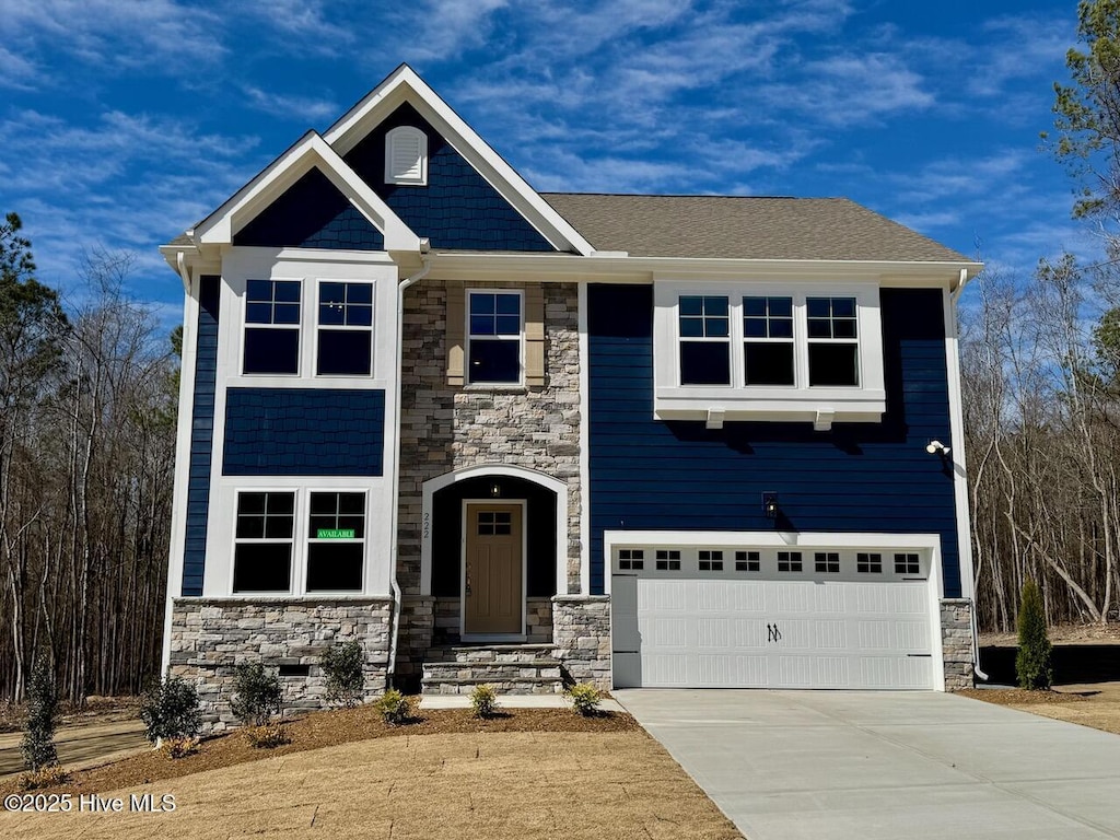 craftsman inspired home with a garage, stone siding, and concrete driveway