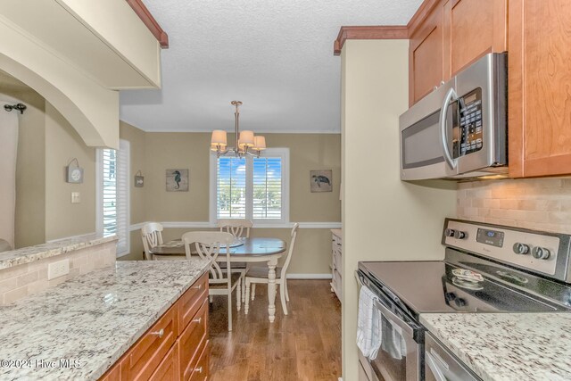 kitchen featuring backsplash, an inviting chandelier, dark wood-type flooring, and appliances with stainless steel finishes