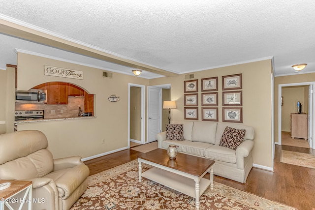 living room featuring crown molding, wood-type flooring, and a textured ceiling