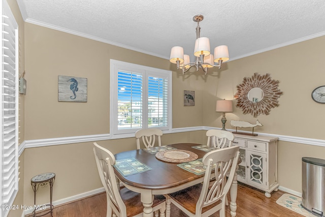 dining area with a notable chandelier, light hardwood / wood-style floors, ornamental molding, and a textured ceiling