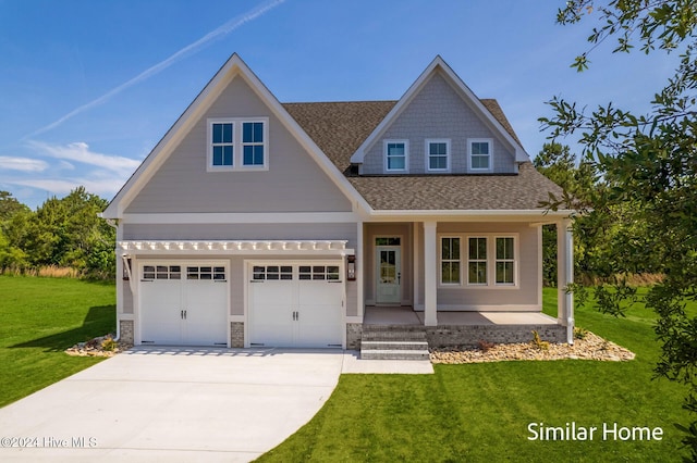 craftsman-style house featuring a porch, a shingled roof, driveway, stone siding, and a front yard