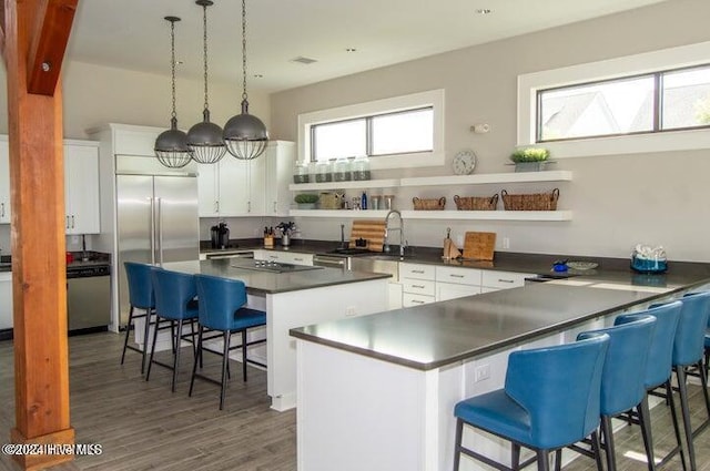 kitchen featuring decorative light fixtures, white cabinets, dark hardwood / wood-style flooring, a kitchen breakfast bar, and a center island