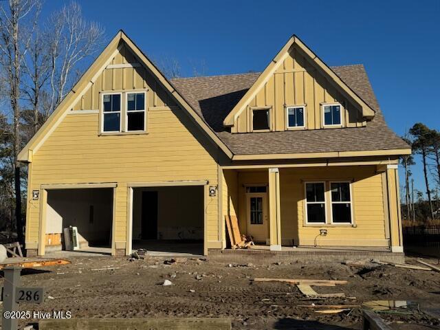 back of property with a garage and covered porch