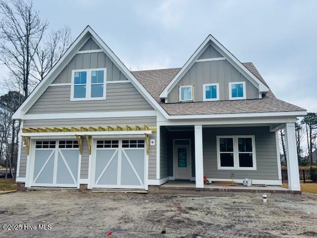 view of front of property featuring a garage, driveway, roof with shingles, a porch, and board and batten siding