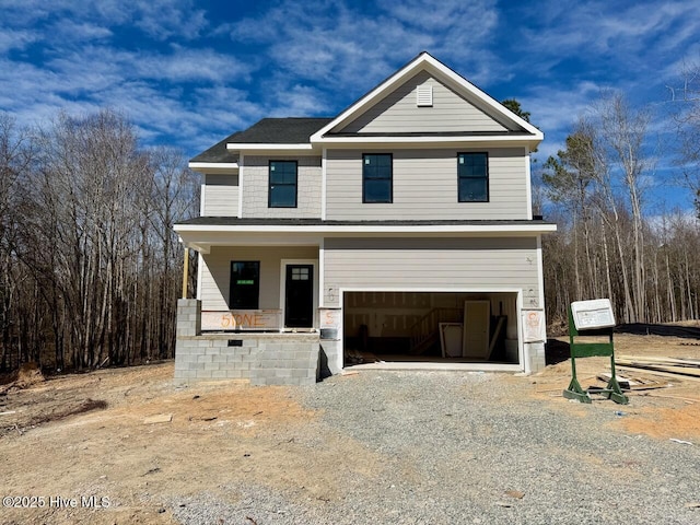 view of front of property featuring a porch, gravel driveway, and an attached garage