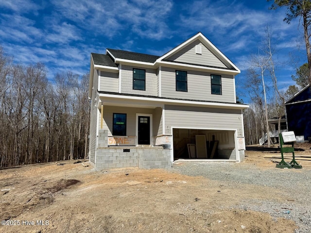 view of front of house with dirt driveway, a porch, and an attached garage