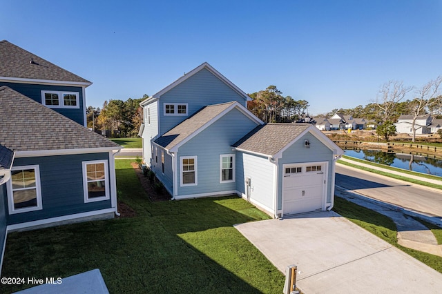 exterior space featuring a front lawn, a garage, and a water view