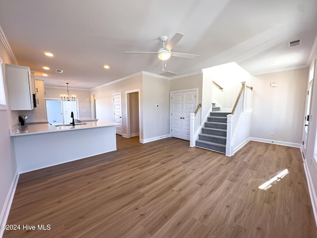 unfurnished living room featuring ceiling fan with notable chandelier, sink, wood-type flooring, and ornamental molding