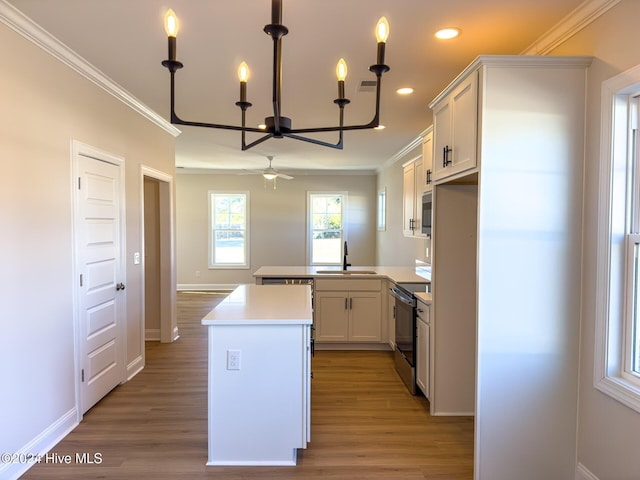 kitchen featuring kitchen peninsula, sink, white cabinetry, range with electric cooktop, and ceiling fan with notable chandelier