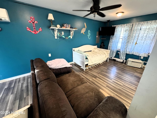 bedroom with hardwood / wood-style flooring, ceiling fan, and a wall mounted AC