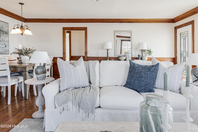 living room featuring a chandelier, a textured ceiling, wood finished floors, wainscoting, and crown molding