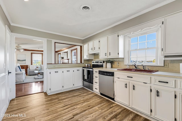 kitchen featuring light wood-type flooring, ornamental molding, a sink, and appliances with stainless steel finishes