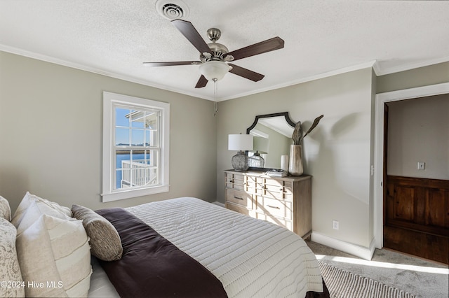 carpeted bedroom featuring a textured ceiling, a ceiling fan, baseboards, visible vents, and crown molding