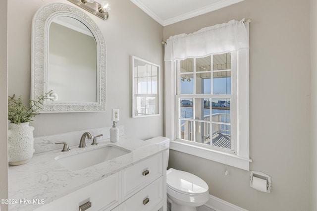 half bathroom with baseboards, crown molding, vanity, and toilet