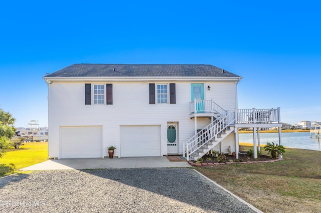 view of front of home with roof with shingles, a front lawn, an attached garage, stairs, and gravel driveway
