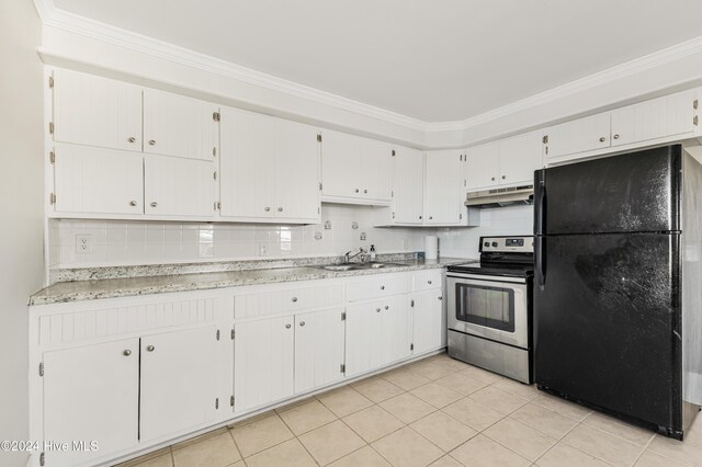 kitchen with white cabinets, black refrigerator, crown molding, a brick fireplace, and light tile patterned floors