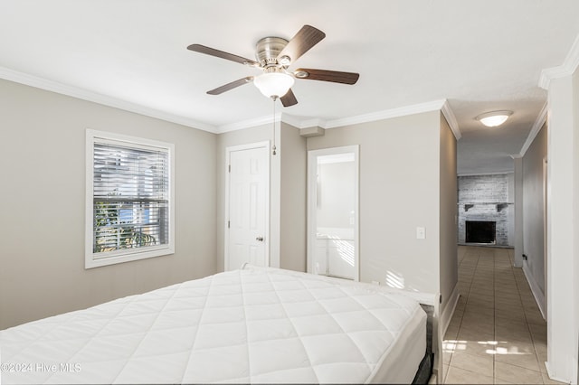 bedroom featuring a ceiling fan, light tile patterned floors, a fireplace, baseboards, and ornamental molding