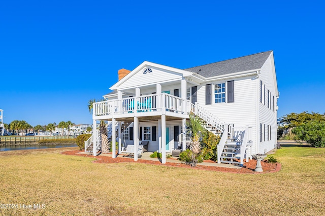 back of house with a lawn, a patio area, and a deck with water view