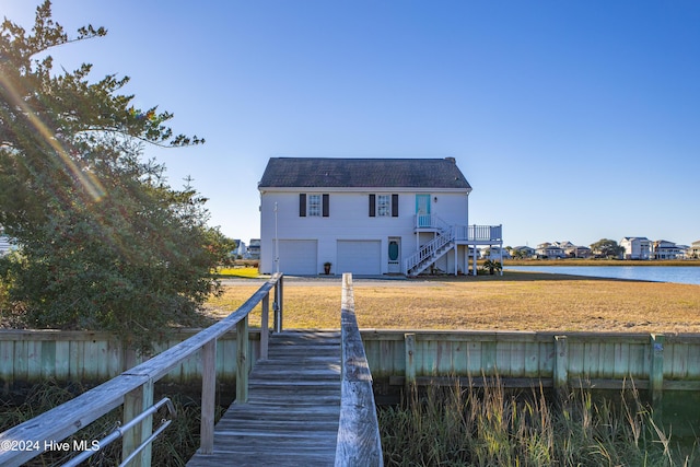 rear view of house with a garage, driveway, a water view, and stairway