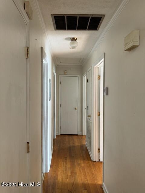 corridor with light hardwood / wood-style floors and crown molding