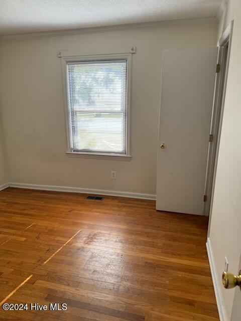 unfurnished room featuring hardwood / wood-style flooring and crown molding