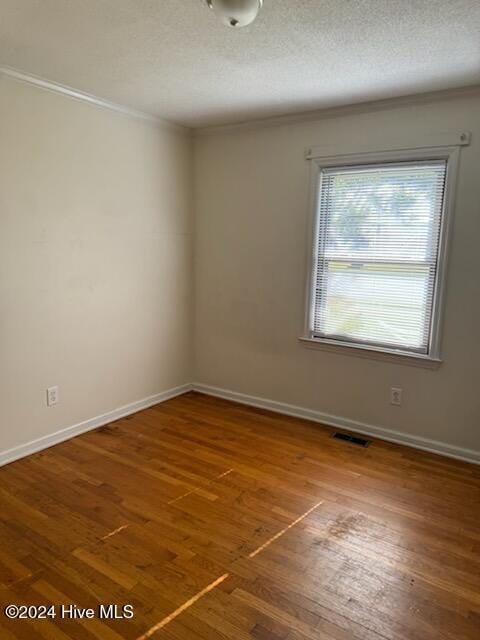 spare room with hardwood / wood-style floors, crown molding, and a textured ceiling