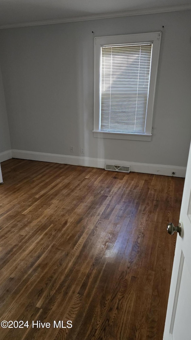 empty room featuring dark hardwood / wood-style flooring and ornamental molding