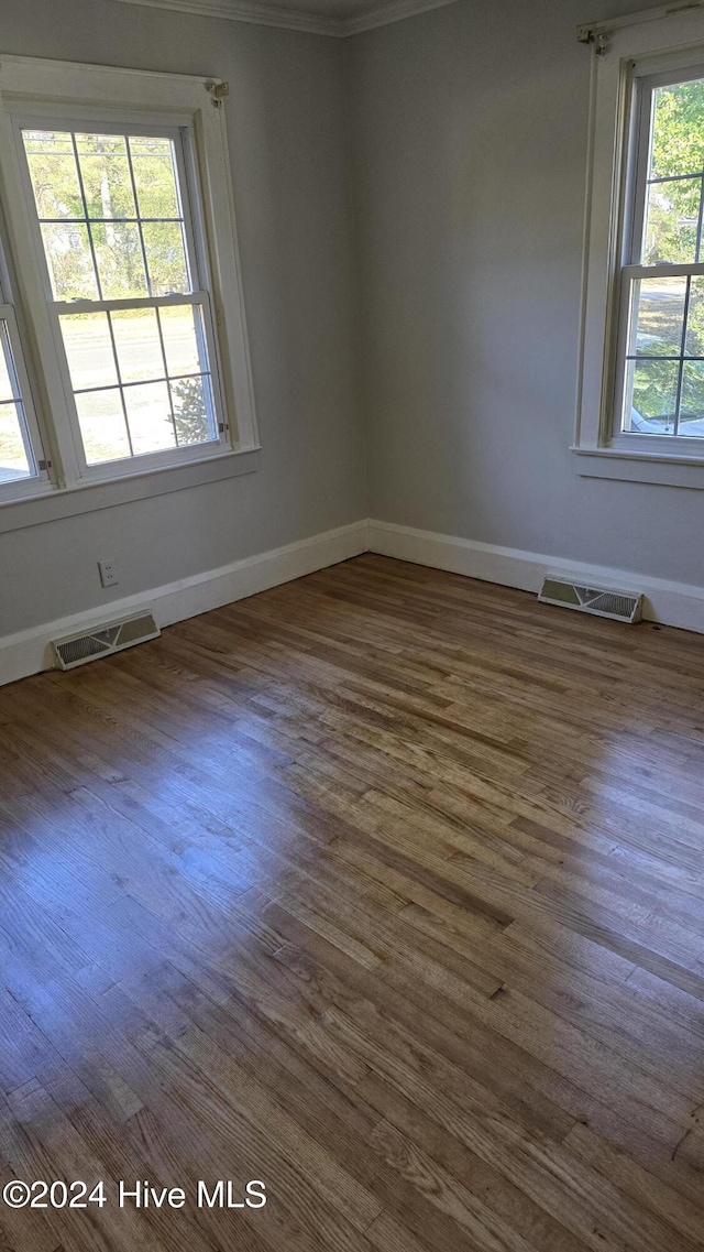 unfurnished room featuring dark hardwood / wood-style flooring, a healthy amount of sunlight, and ornamental molding