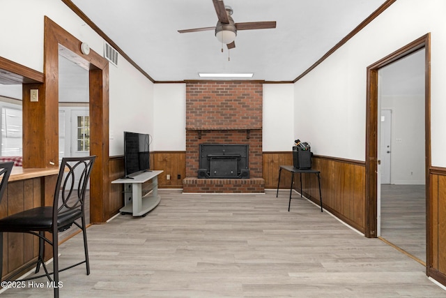 living room with ornamental molding, light wood-type flooring, and ceiling fan