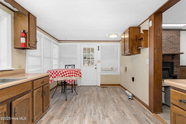 kitchen with light hardwood / wood-style flooring, crown molding, and a fireplace