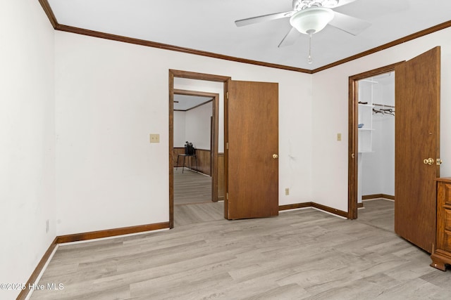 unfurnished bedroom with a closet, light hardwood / wood-style floors, ceiling fan, ornamental molding, and a spacious closet