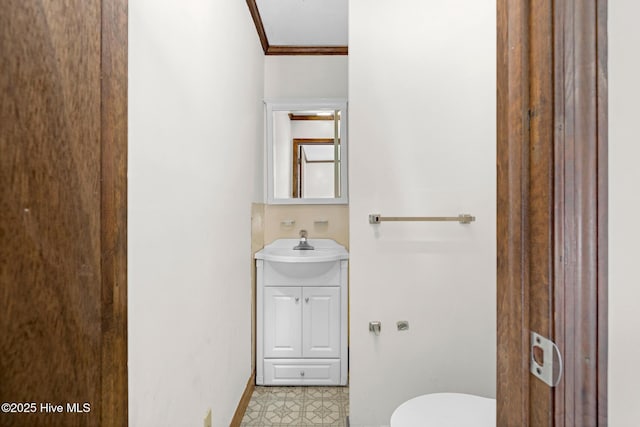 bathroom featuring toilet, ornamental molding, and vanity