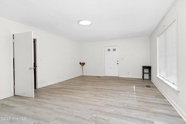 empty room with light hardwood / wood-style floors and crown molding