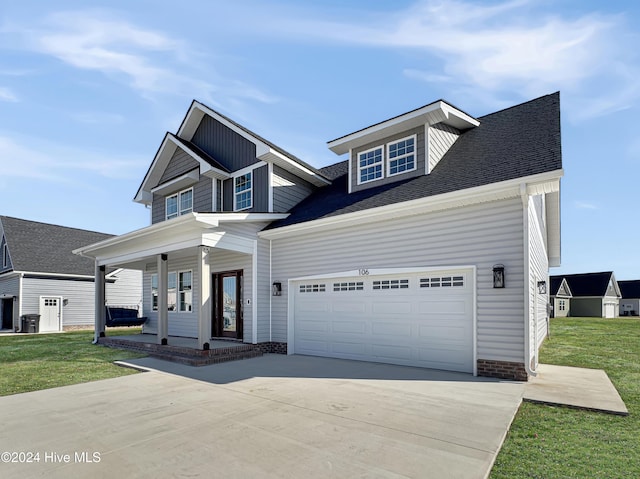 view of front of property featuring a garage, covered porch, and a front lawn