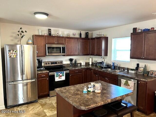 kitchen with a breakfast bar, a center island, dark brown cabinets, and appliances with stainless steel finishes