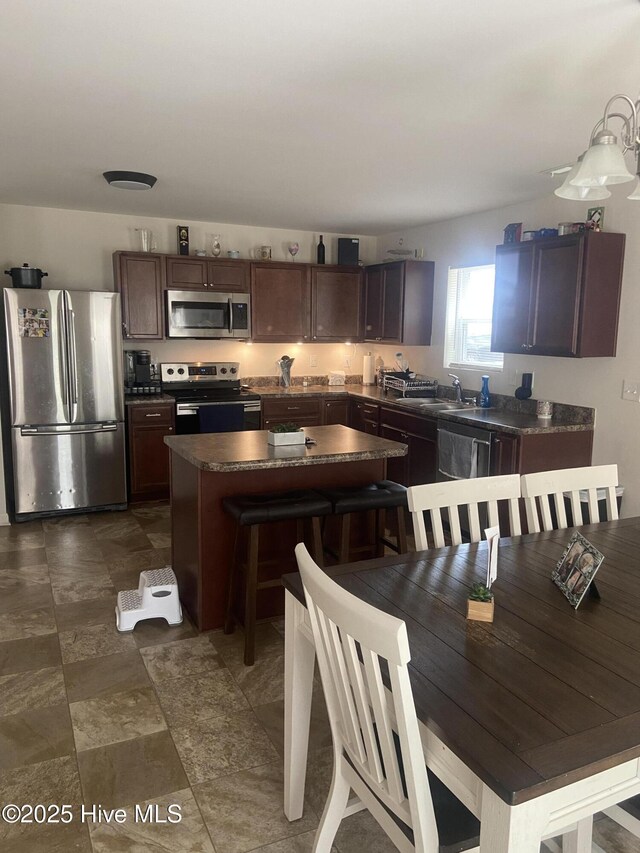 49 Patrick Henry Cir NW, Supply, NC 28462 - kitchen with appliances with stainless steel finishes, dark countertops, a kitchen island, a sink, and dark brown cabinets