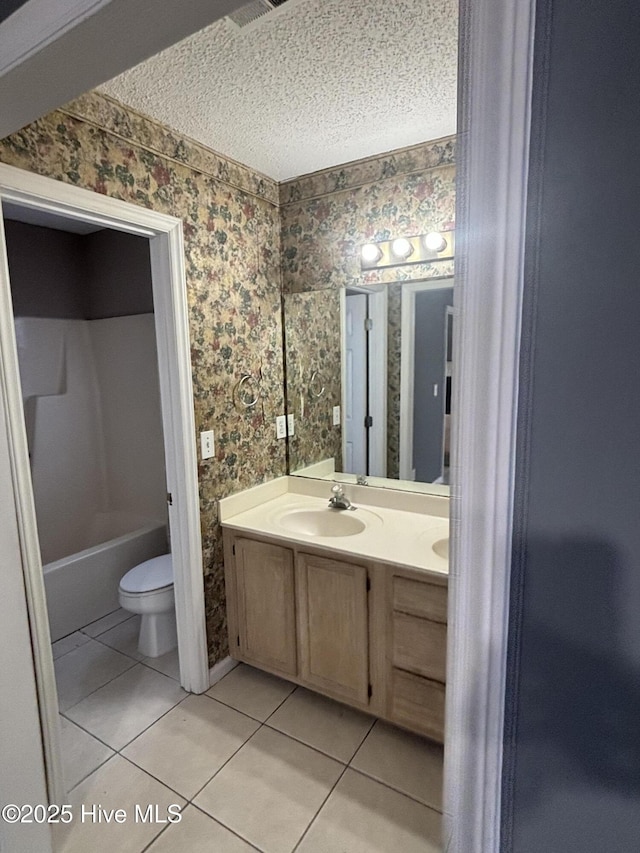 bathroom featuring vanity, tile patterned flooring, toilet, and a textured ceiling