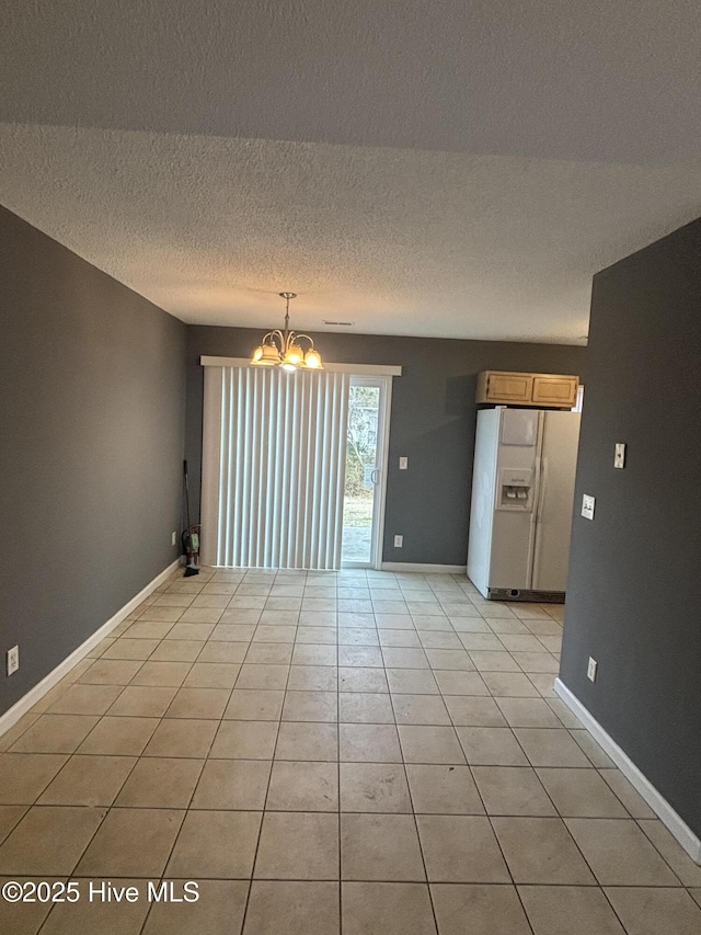 empty room featuring light tile patterned flooring, a textured ceiling, and a chandelier